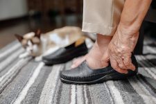 Elderly woman swollen feet putting on shoes